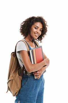 Image of pretty african american woman wearing backpack smiling and holding exercise books