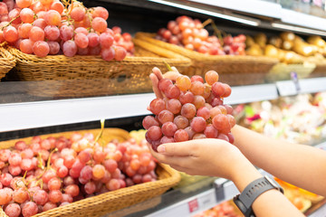 Hands that are picking fruits and vegetables from the shelf to select quality products. Buy back to cook or bring to eat In the mall The concept of buying healthy food