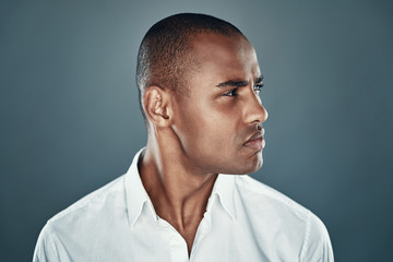 Fototapeta premium Confident look. Handsome young African man in shirt looking away while standing against grey background