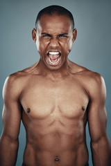 Fototapeta premium Furious man. Shirtless young African man looking at camera and shouting while standing against grey background