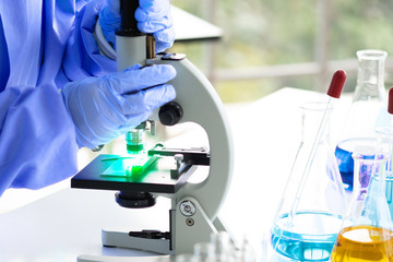 The scientist's hand holds a microscope of chemicals in the lab to prepare specimens to test in the laboratory blue background, science research and development concept