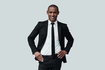 Perfect in every way. Handsome young African man in formalwear looking at camera and smiling while standing against grey background