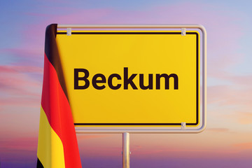 Beckum. Gelbes Schild/Ortsschild. Flagge von Deutschland hängt darüber. Himmel mit Sonnenuntergang oder Sonnenaufgang