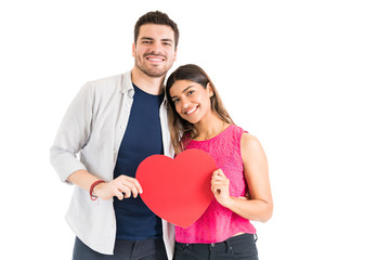 Fototapeta na wymiar Good Looking Couple Holding Heart Cutout In Studio
