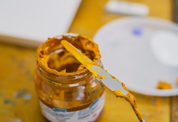 Dirty glass jar with a palette knife. Closeup