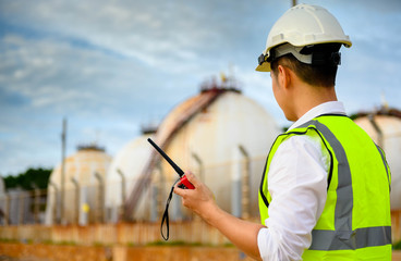 Engineer with safety helmet and radio communication with oil refinery industry plant , engineering...
