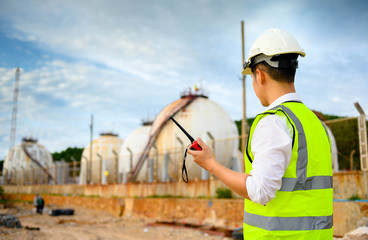 Engineer with safety helmet and radio communication with oil refinery industry plant , engineering concept