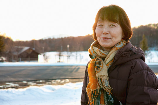 An Older Lady Smiling While Looking At The Winter Scenery