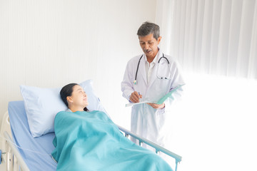 doctor talked about the illness of the female patient in the hospital, the doctor talked with a smile to make the patient relax.