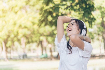 Leisure cheerful wellness woman Concept. Happy teenage woman listening to music wear headphones from smartphone outdoor in the park. Music mental therapist for wellness woman.