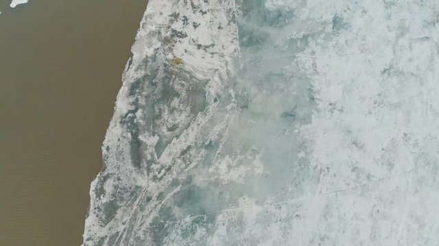 half frozen river with exciting patches of open water in ice and ridges images on cold winter day vertical aerial view