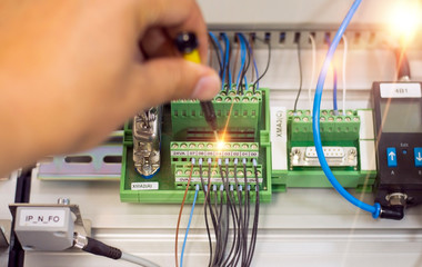 Selective focus. Electronic technician repair electronic equipment. Man hand screw electrical terminal block.
