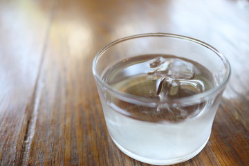 木のテーブルに置いた氷水のグラス