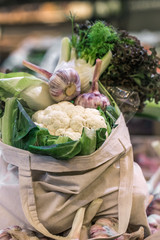 Display of fresh ripe organic broccoli, salad and greens in cotton bag at the weekend farmer's market
