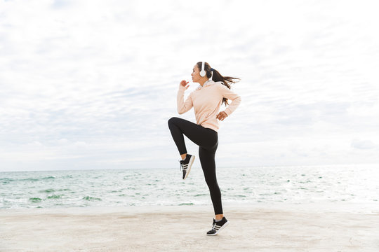 Attractive young asian sportswoman exercising at the seashore