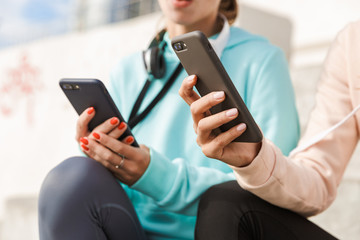Two pretty smiling fitness women wearing hoodies