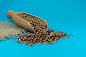 Flax seeds spilling from a wooden scoop
