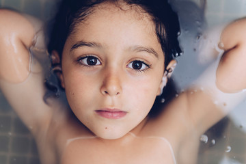 portrait of a pretty little girl lying in the tub
