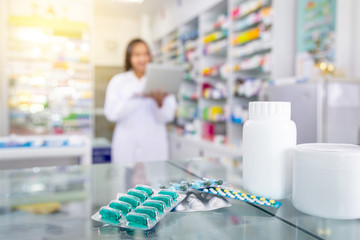 Capsules de médicaments et flacons de médicaments blancs sur table en pharmacie avec arrière-plan flou du pharmacien et de la pharmacie.