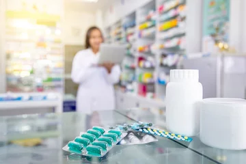 Foto auf Acrylglas Apotheke Kapselmedizin und weiße Medizinflaschen auf dem Tisch in der Drogerie mit unscharfem Hintergrund von Apotheker und Apotheke.