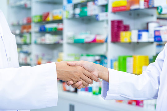 Close up picture of doctor and pharmacist shaking hands in the pharmacy.