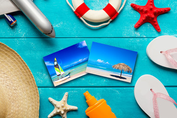 Summer holidays and vacation travel concept. Sunscreen lotion bottle, straw hat, flip flops, starfish, life buoy, plane and tropical beach photos on blue background. Photos available in my portfolio