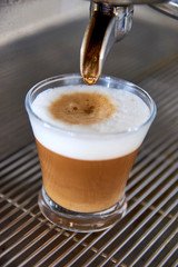 Waiter preparing spanish espresso coffee called "Cortado". Coffee mixed with milk (creamy Latte with white foam on top). Two layers of color. Bar vacation holidays workplace worker elaboration