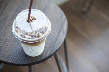 Angle view of No syrup ice Latte on wood chair out side coffee shop.
