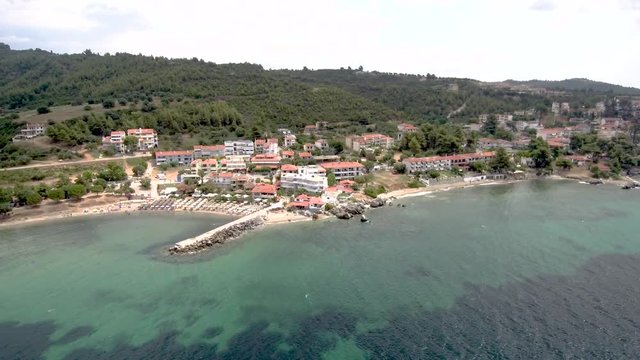 Aerial view of small turquoise beach with rocks under a tourist village in the area of Agia Paraskevi Halkidiki, Greece ,sideways movement by drone