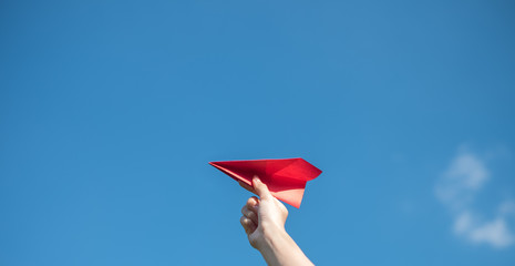Men's hands hold a red paper rocket with a bright blue background.