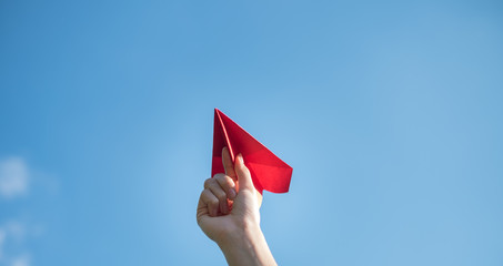 Men's hands hold a red paper rocket with a bright blue background.