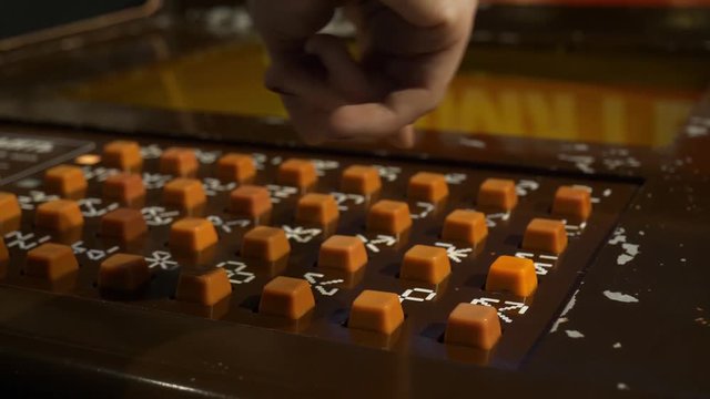 Slot machine brown panel with plenty of orange buttons and white symbols over them dedicated to train memory by memorizing different combination, where female's hand is pressing them in amusement park