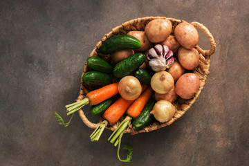 Fresh vegetables of the new crop in a basket on a dark rustic background. Top view, flat lay, copy space.