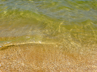  A fragment of a sandy beach with a wave running over it.              