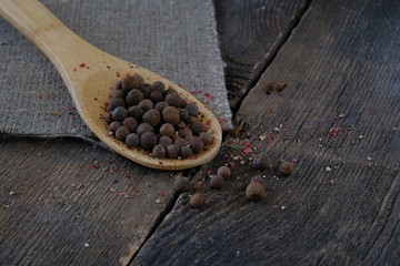 Black pepper on a wooden spoon on the background of the old table.