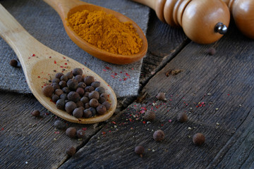 Black pepper and turmeric on a wooden spoon on the background of the old table.