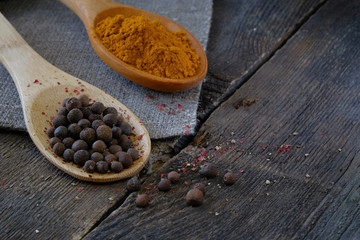 Black pepper and turmeric on a wooden spoon on the background of the old table.