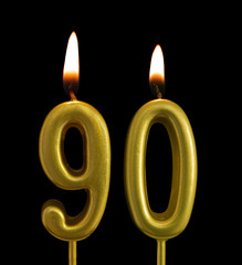 Burning golden birthday candles isolated on black background, number 90