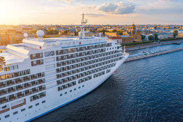 Cruise liner moored at the embankment in the waters of the river in the evening at sunset. Aerial...