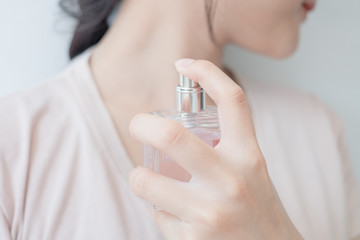 woman is spraying perfume at the neck.
