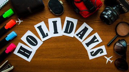 Holidays word holidays letters inscription wooden table top view. Preparation for the vacation...