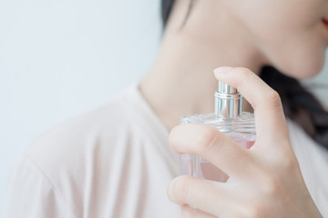 woman is spraying perfume at the neck.