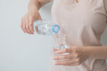 Woman's hand holding a bottle of water Pouring water into a glass