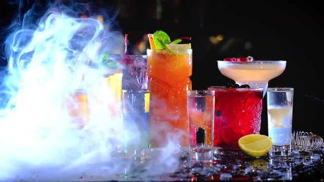 Close up focus shift view of colorful hookahs and fruit hookah stand on the bar counter. hookah smoke closes cocktails