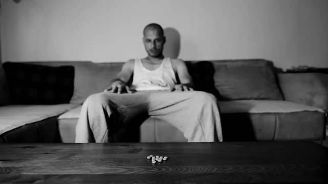 Depressed man suffering from suicidal depression want to commit suicide by overdose taking strong medicament drugs and pills pain killers sitting in his dark room selective focus moody dramatic look