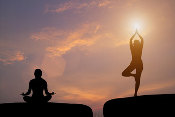The silhouette of a woman practicing yoga on a rock during a beautiful sunset