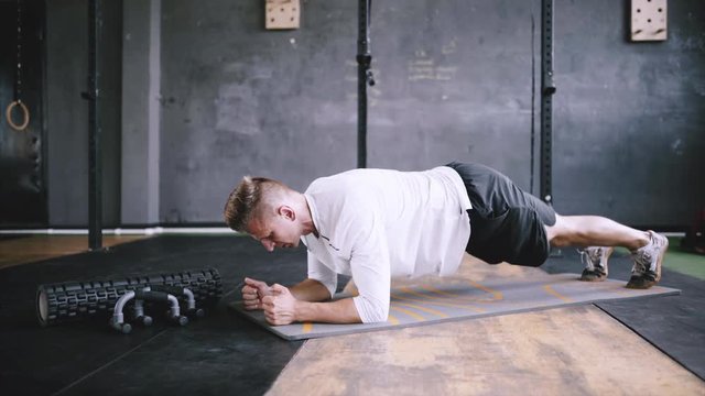 High performance triathlon or marathon exercises. Man in good fit does plank alternating leg lifts for improving sports training. Available exercises for office workers. Intermediate no equipment