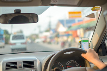 Man sit in the car hand is driving the car on the road.open GPS application. travel to He is...