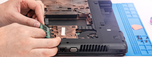 Engineer makes dismantling of RAM for disassembling and repairing a laptop.