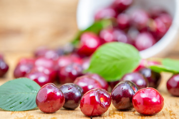 Fresh cherries in the white bowl on wood table